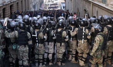 Rows of military police in riot helmets line up in front of demonstrators in Bolivia