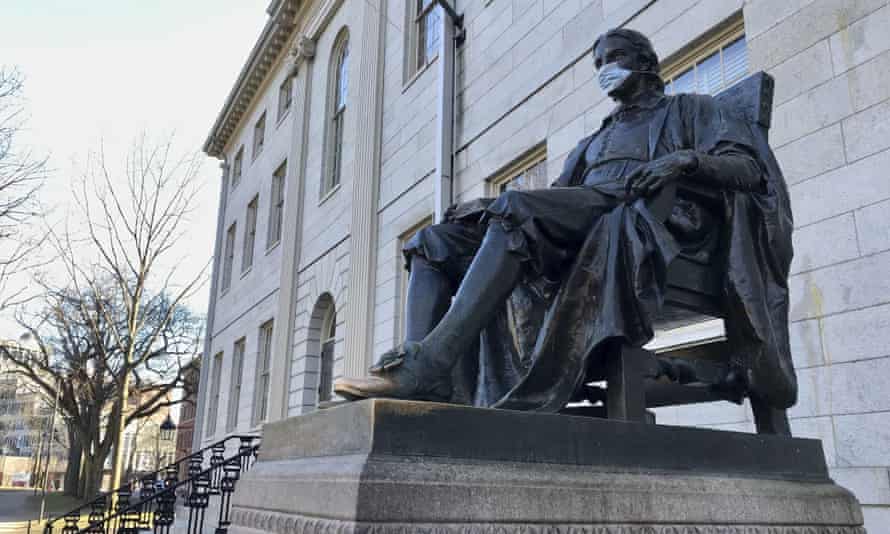 john harvard statue wearing a mask on harvard's campus