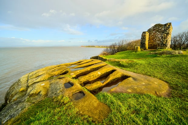 ‘Stone coffins’ and ruins of Saint Patrick’s Chapel Heysham Head Lancashire. Morecambe Bay beyond