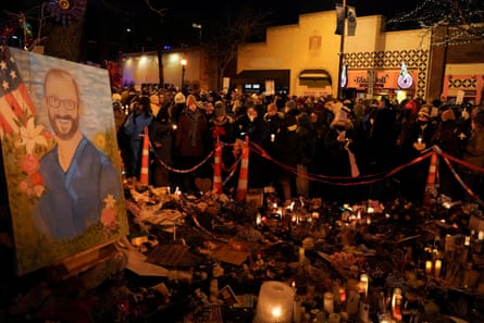 people stand near a memorial featuring a large painting of a nurse