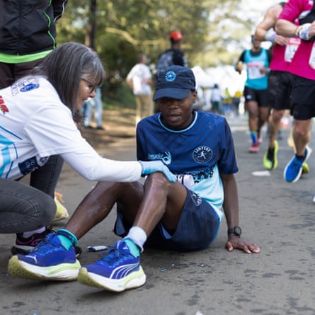 A runner receives a leg-rub from a volunteer along the route