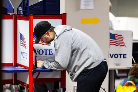 A man fills out a voting form in a voting booth.