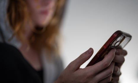 A young woman looks down at her smartphone