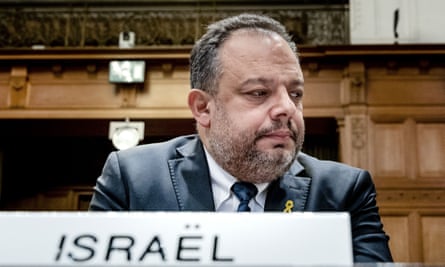 Tal Becker sitting behind a sign reading: ‘Israël’
