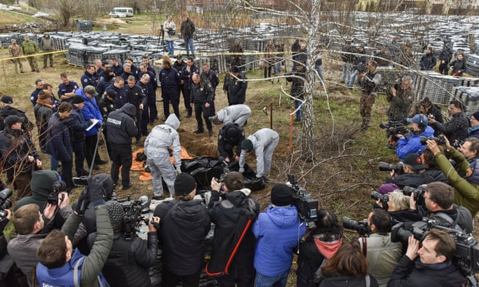 Members of an international team of war crimes prosecutors visit a mass grave in Bucha, Ukraine, in April. Investigators found mass graves in the city, where the bodies of civilians, tortured and murdered, had been buried.