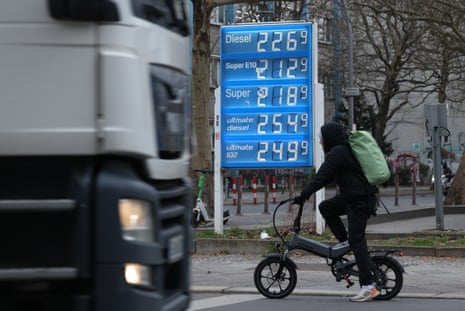 A truck and a cyclist pass a petrol station that shows gas prices well over €2 per litre in Berlin, Germany.