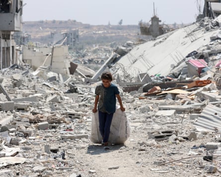 A girl pulls a sack along the ground, surrounded by destructions.