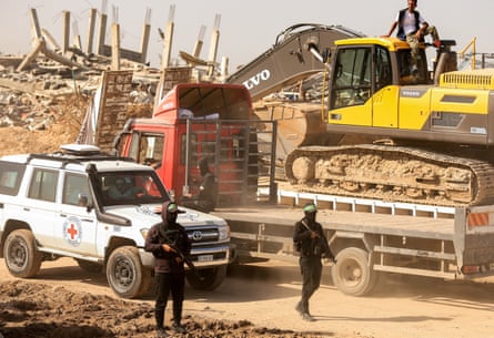 Two Hamas militants hold rifles as they escort a Red Cross vehicle
