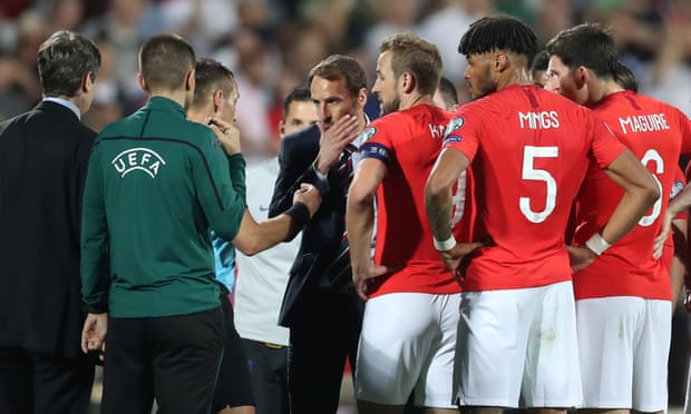 The England players and manager Gareth Southgate speak to referee Ivan Bebek as the match is stopped during the first half.