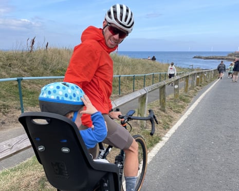 Paddy Maddison cycling with a child in a bike seat along the coastal path