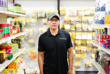 a man surrounded by shelves neatly stocked with food