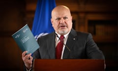 The ICC prosecutor Karim Khan speaks at a lectern. He is holding up a booklet, Policy on Complementarity and Cooperation
