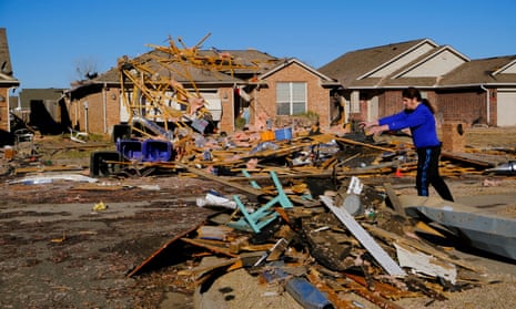 A man tosses debris into a pile as he cleans up damage caused by tornadoes that hit in Norman, Oklahoma.
