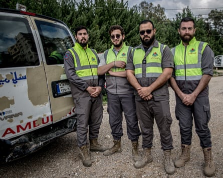 Four paramedics stand next to a damaged ambulance