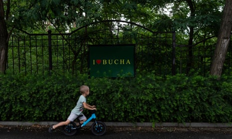 Un niño monta su bicicleta frente a un cartel de 'I Love Bucha' en Bucha.