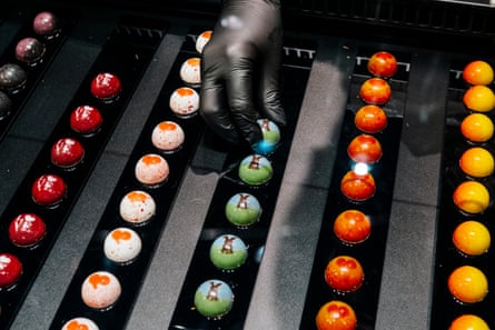 Worker arranges neat rows of small pralines