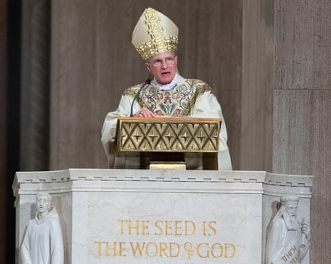 Archbishop Timothy broglio, wearing white and gold robe, speaks into microphone at church