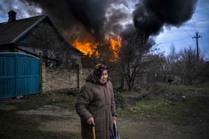 An elderly woman stands near a burning building following shelling in Kostyantynivka in the Donetsk region of Ukraine