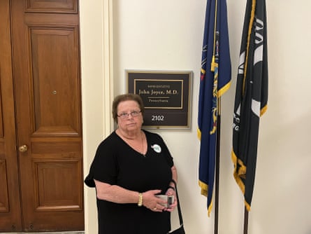 a woman outside a door next to two flags