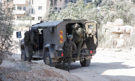 Israeli soldiers in camouflage get into a military vehicle