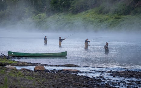 Four people fly fishing in the Miramichi river with mist rising about them