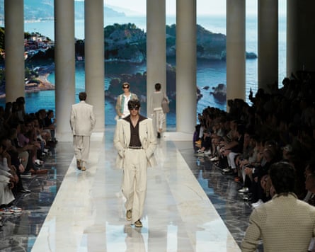 Male models on the runway, coastal imagery behind them