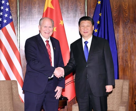 Men shake hands in front of flags
