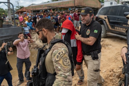 Federal police escort Pelado on to a boat as crowds watch
