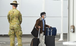 A member of the Defence Force watches over as returning overseas travellers are ushered towards waiting buses for the beginning of their 14-day quarantine after arriving at Sydney International Airport in Sydney, Australia, 29 March 2020.