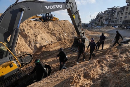 People dressed in black, their faces covered, walk near a bulldozer