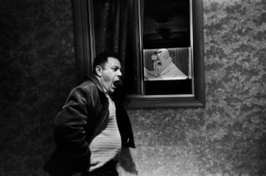 A man standing by a window, with a cartoon image of a man behind him