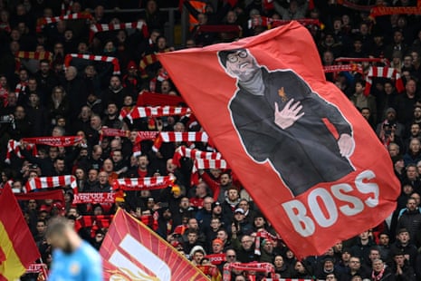 Los fanáticos del Liverpool sostienen bufandas y ondean banderas entre la multitud.