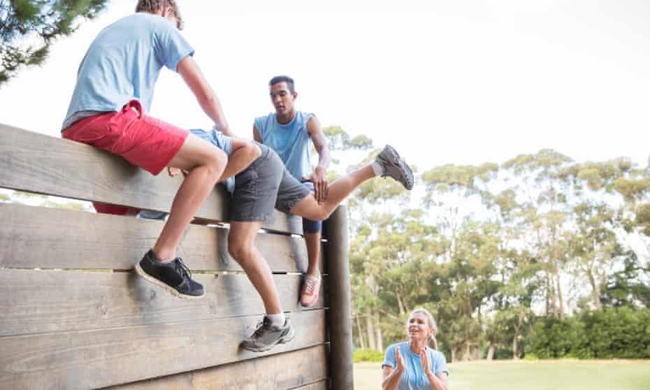 Person being helped over an assault course wall