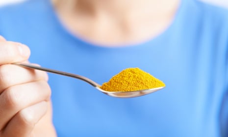 Woman with spoonful of tumeric powder
