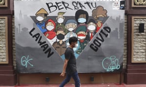 A man walks past a coronavirus-themed mural in Jakarta, Indonesia, as the country tightens travel curbs in preparation for Omicron arrival.