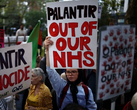 A protester holds a sign reading "Palantir Out Of Our NHS" among demonstrators with placards in London