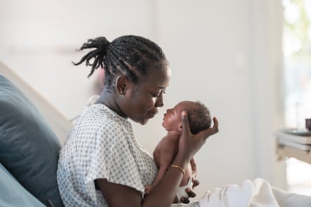 Black Mother Holds Newborn Baby in Hospital Bed, Tender Family Moment of Newborn CareA Black mother in a hospital gown lovingly cradles her newborn, capturing a tender, intimate moment of motherhood, care, and family connection in a clinical setting.