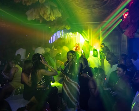 Green and yellow lights beam out across a dark club filled with women in going-out clothes and men in white T-shirts