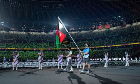 A volunteer carries the national flag of Afghanistan during the opening ceremony.
