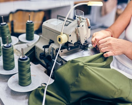 A person sewing green fabric using industrial overlock machine