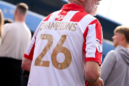 A Lincoln fan wears a home shirt with Champions 26 on the back of it in gold lettering.