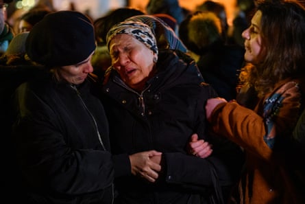 A woman cries and is consoled by two other people