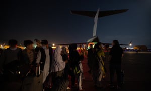 Australian citizens and visa holders form a line to board the Royal Australian Air Force C-17A Globemaster as Australian Army Infantry personnel provide security at Hamid Karzai International Airport.