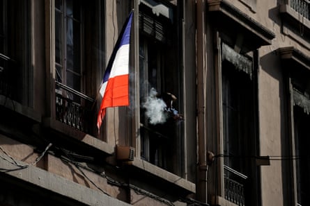 A man smokes next to a French flag in Lyon