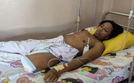 Aina Sarobidy Randriamiharisoa connected to a drip in his hospital bed. A drink with a straw in it is resting in his armpit
