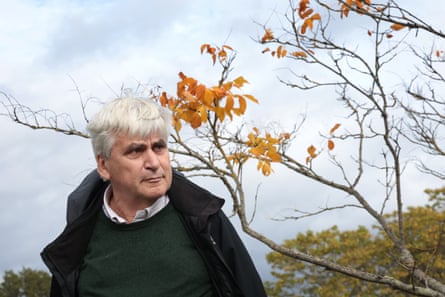 Guy Barter standing in front of a tree that has nearly lost all of its leaves.
