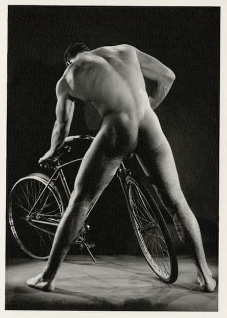 Nude man mending a bike