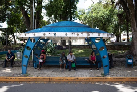 Locals wait for a bus in the shade of one of Varginha’s spaceship-shaped bus stops