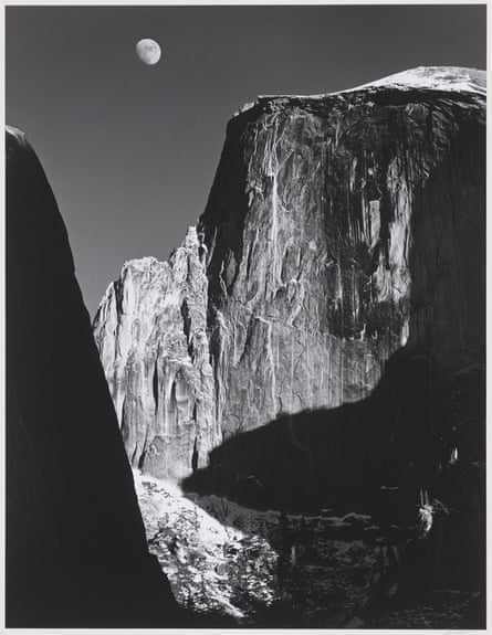 black and white image of a cliff face with the moon above it