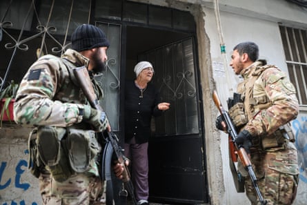Two soldiers talk to a woman at her front door